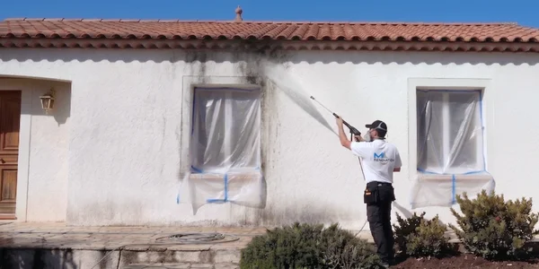 Technicien appliquant un nettoyage à pression régulé à Marseille pour désincruster efficacement les salissures sur une surface extérieure.
