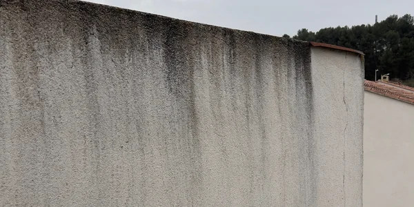Photo du haut d'un mur de séparation avec présences de traces noires causé par la pluie sur une façade non hydrofugé.
